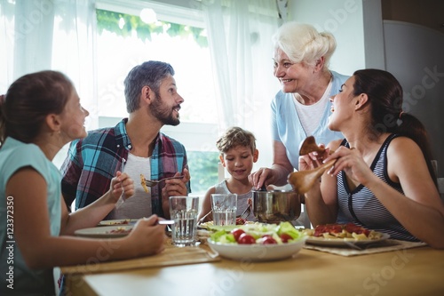 Elderly woman  serving meal to her family