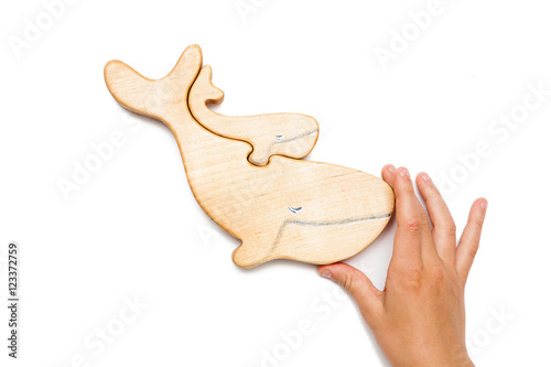 Wooden puzzle in the form of a whale and little whale with hands isolated on white.
