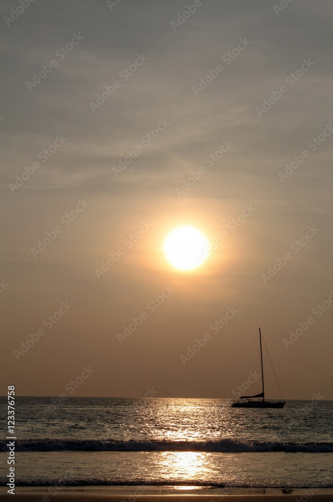 silhouette of a sailingboat at sunset on the seashore