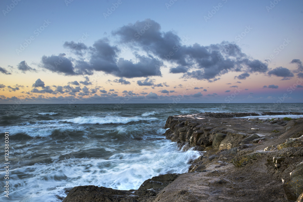 Portwrinkle at sunrise with waves lashing over rocks and cloudy sky, cornwall ,uk