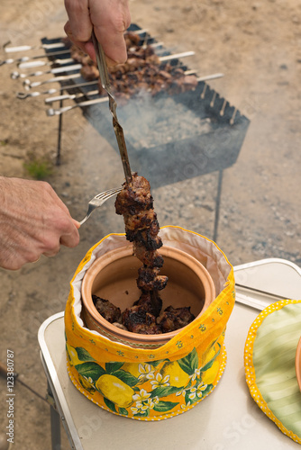 The man removes a shish kebab from a skewer