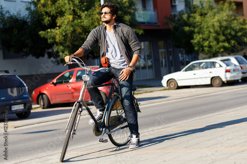 Young handsome guy with a bicycle on street.
