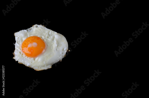Fried egg on a black background, delicious breakfast.