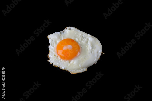 Fried egg on a black background, delicious breakfast.