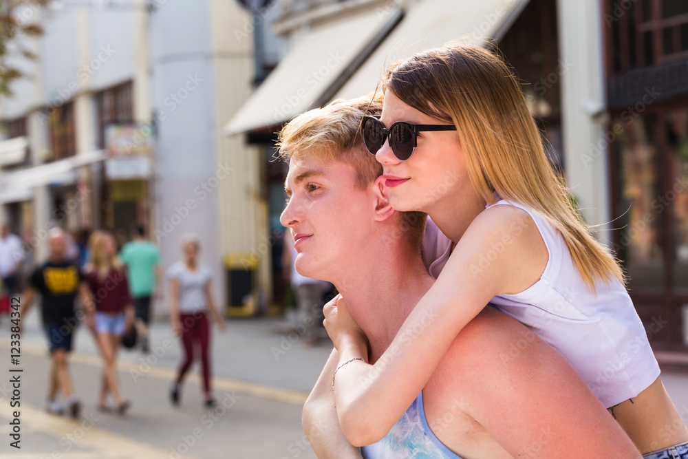 young couple having piggyback in summer in walking street young couple having piggyback in summer in walking street