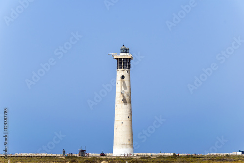 Faro de Morro Jable, an european lighthouse located on one of the most famous beaches on Fuerteventura. Landscape with absolutely clear blue sky and the historical building
