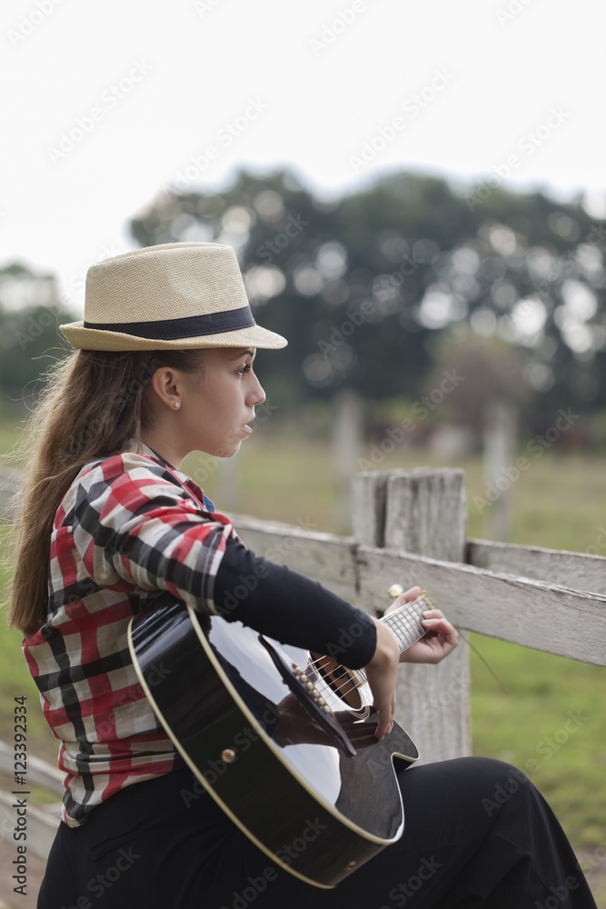 A young girl with a guitar in the nature