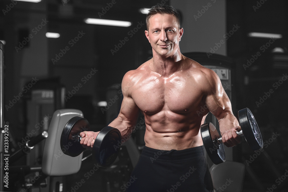Handsome athletic fitness man posing and trains in the gym. Handsome athletic fitness man posing and trains in the gym.