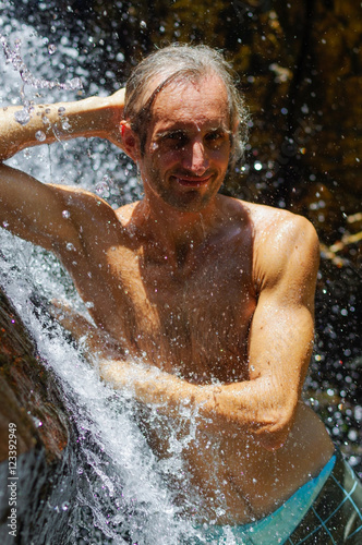 Man taking a relaxing shower under waterfall. outside