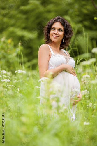 Pregnant woman on nature, smiles)