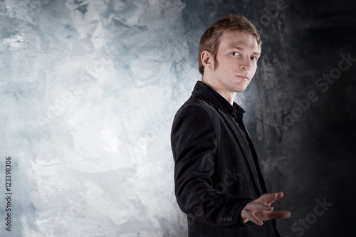 Say no. Young man conducts a dialogue in black suit on textured grey background