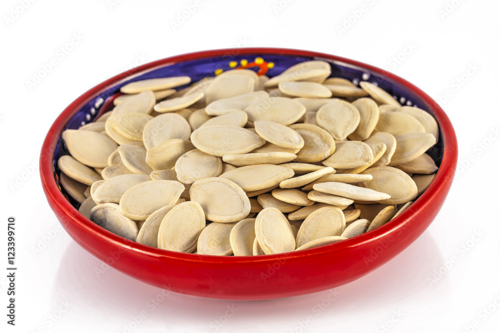 The red ceramic bowl with pumpkin seeds.