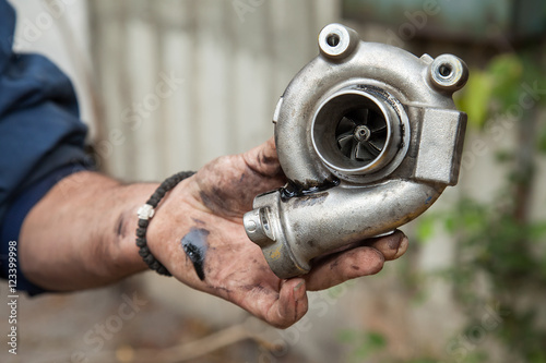 hand of a mechanic holding defective turbine from car engine