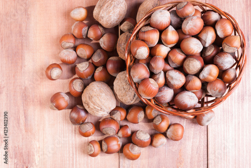 Walnuts, hazelnuts lying in a basket on wooden background. The view from the top.