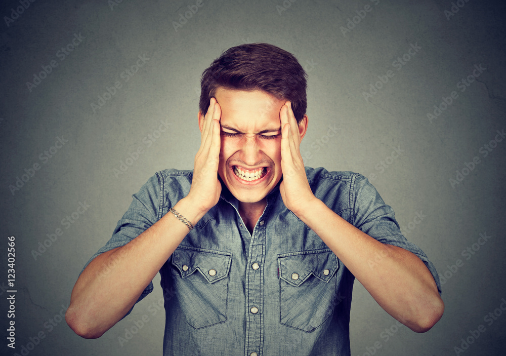 Stressed man with headache isolated on gray wall background Stressed man with headache isolated on gray wall background