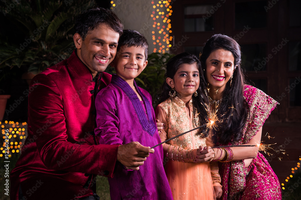 Indian Family in traditional wear playing with sparklers or phuljhadi while  celebrating diwali festival, outdoor Stock Photo | Adobe Stock