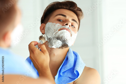 Young man shaving and looki...