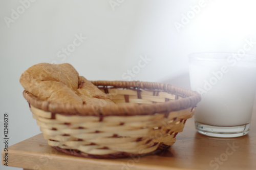 Sweet buns and  Cup of yogurt or glass of milk on a table in wicker basket
