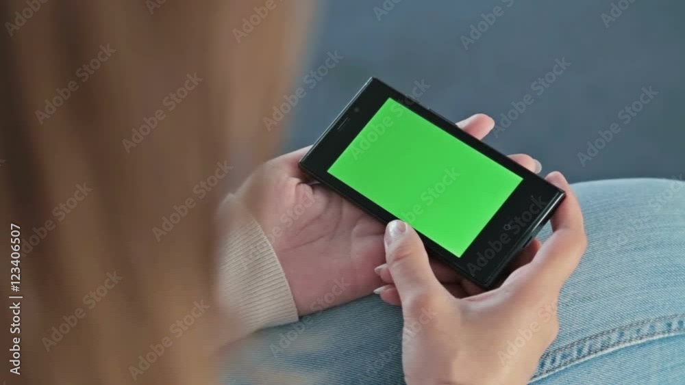 Woman looking at smart phone phone with green screen in the empty conference hall of cruise ship Woman looking at smart phone phone with green screen in the empty conference hall of cruise ship