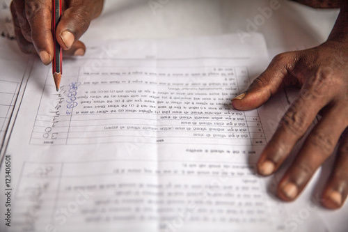 Hands of a farmer in India who fills out an application in Hindi language asking for infrastructure support for his village from the government