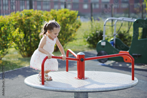Tableau sur toile Little girl playing on the Playground - rides on the carousel.