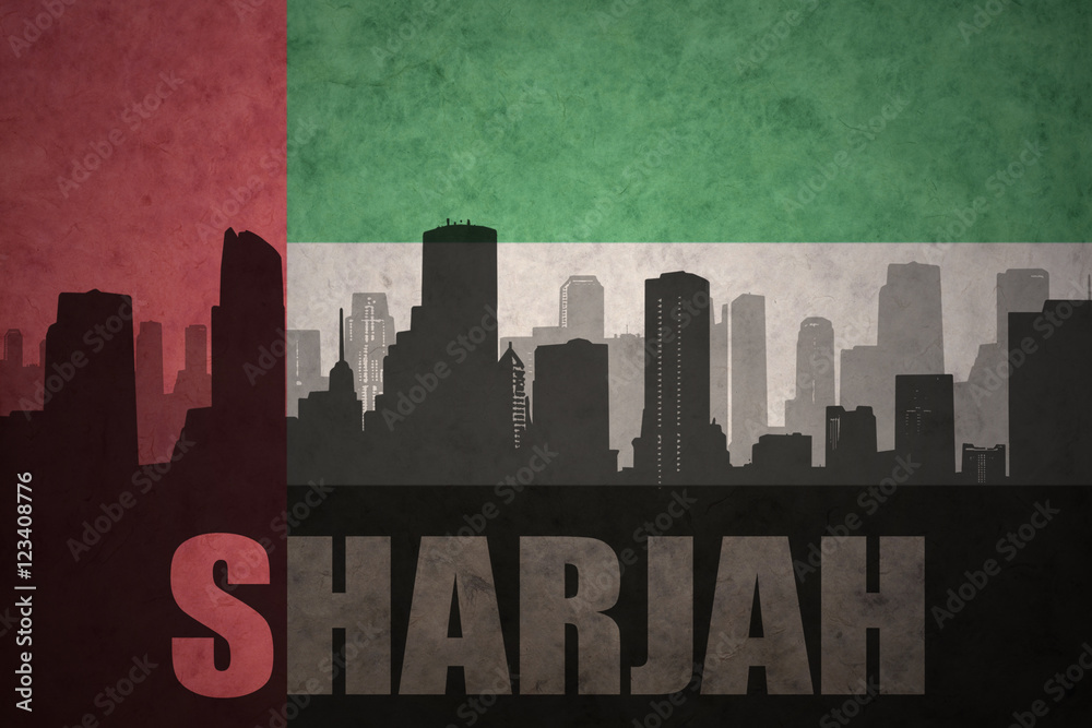 abstract silhouette of the city with text Sharjah at the vintage united arab emirates flag background