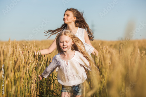 two sisters running on wheat filed