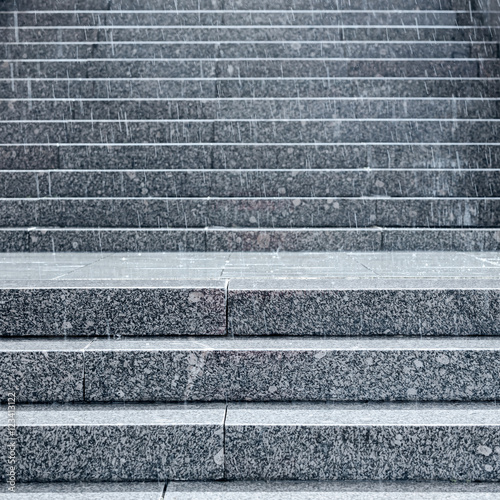 rain splashes on gray granite steps of broad staircase