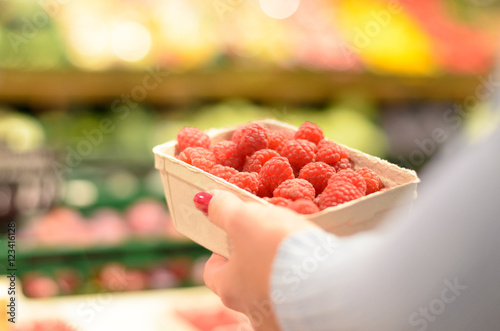 Tableau sur toile Person selecting a punnet of fresh raspberries