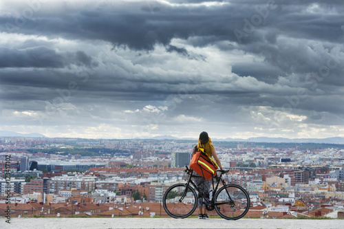 Woman with bike standing over cityscape.