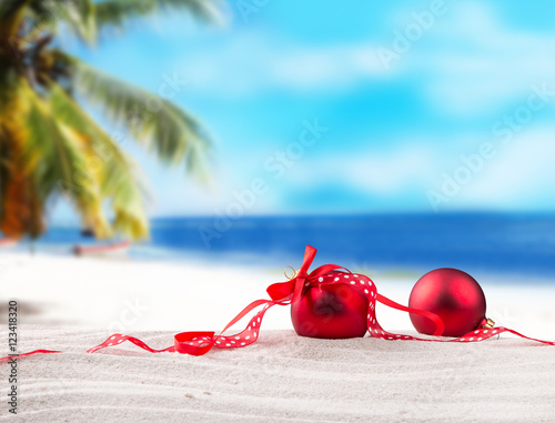 Christmas red balls, ornament on a beach - concept of a warm weather Christmas photo