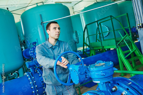 serviceman operating industrial water purification or filtration equipment photo