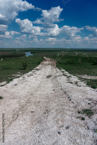 White chalk road among green spaces, landscape with blue sky and clouds. Kostenki village, Voronezh Region photo