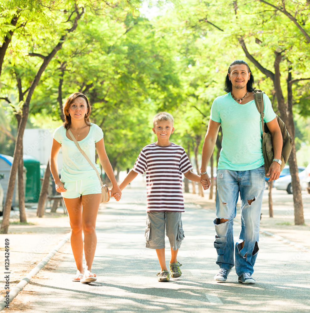 Obraz premium family of three walking in summer park