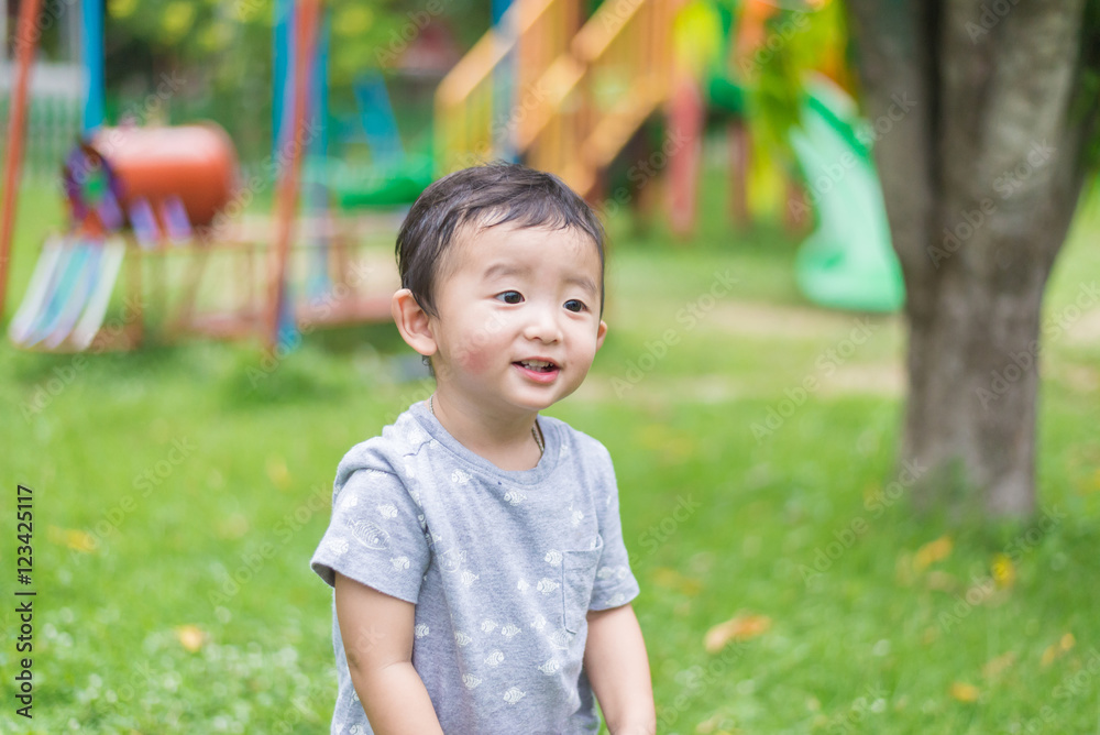 Little Asian kid playing and smiling at the playground under the Little Asian kid playing and smiling at the playground under the