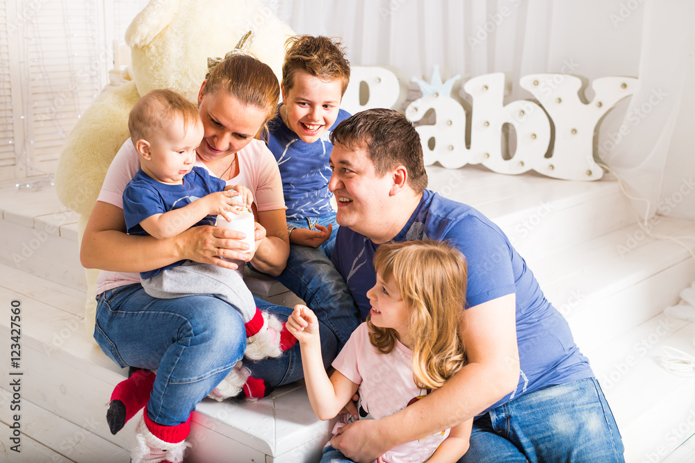 Happy family with 3 children sitting on floor of living room at home Happy family with 3 children sitting on floor of living room at home