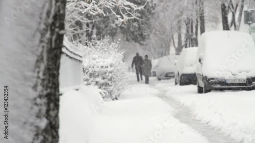 Street Covered In Snow, Car Tracks, People Strugling To Walk. Rack Focus photo