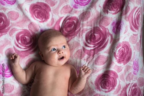 Surprised smiling  baby girl   light pink background with roses