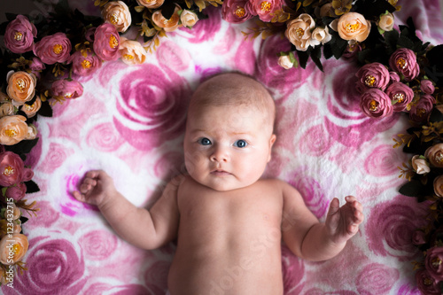 baby girl on a light pink background with roses flowers  close u