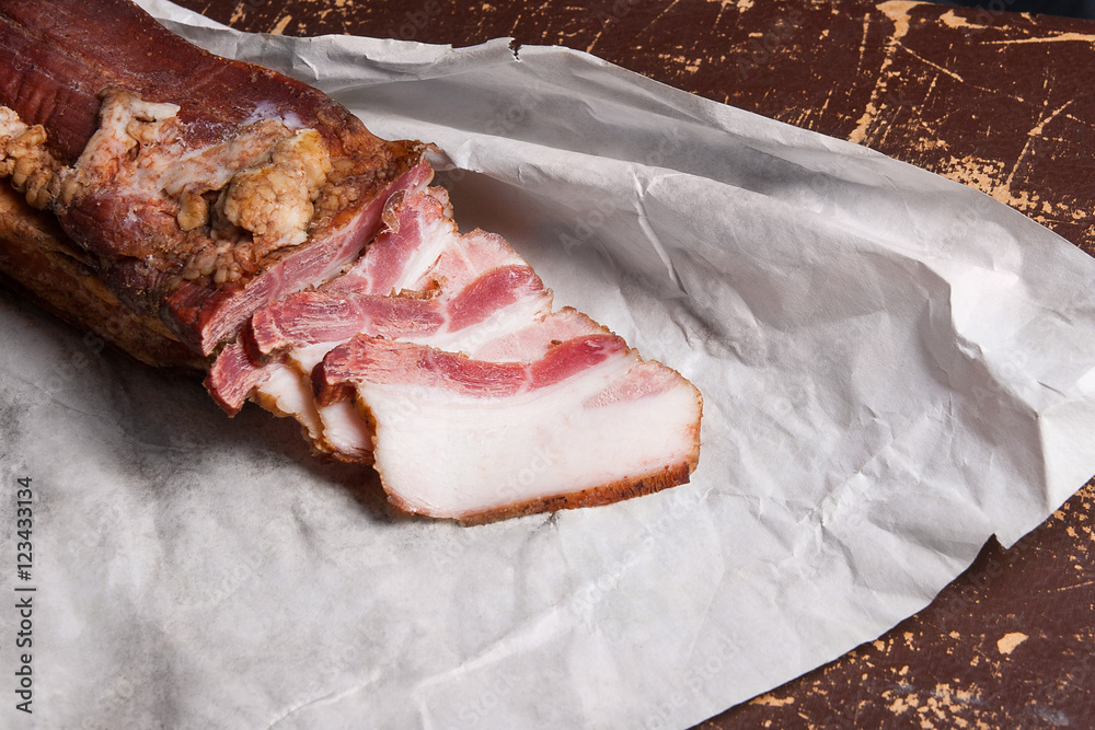 Puff smoked bacon on the packaging paper. Vintage naturmort in a