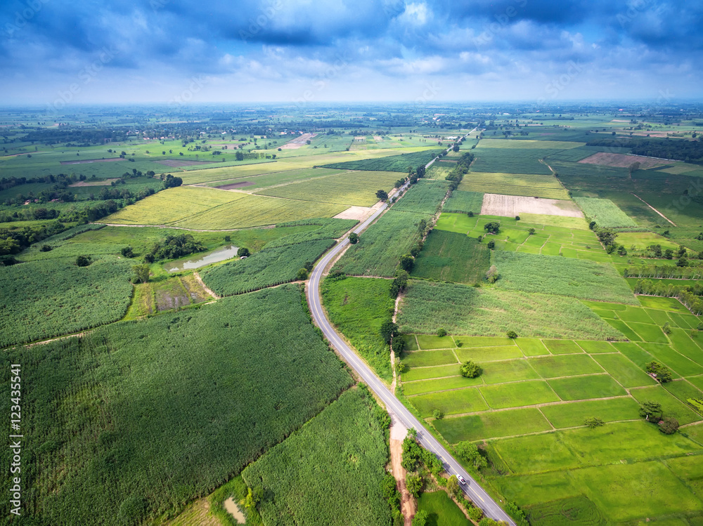 Aerial view of a country road amid fields with a white car