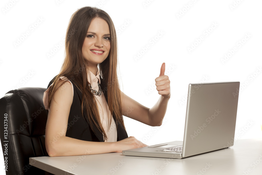 beautiful business woman working on a laptop and showing thumbs up beautiful business woman working on a laptop and showing thumbs up