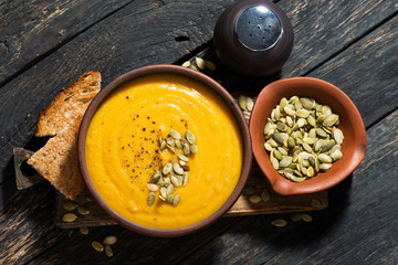 Delicious pumpkin soup on wooden table, top view