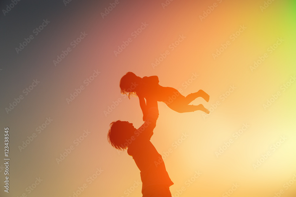 silhouettes of father and little daughter playing at sunset