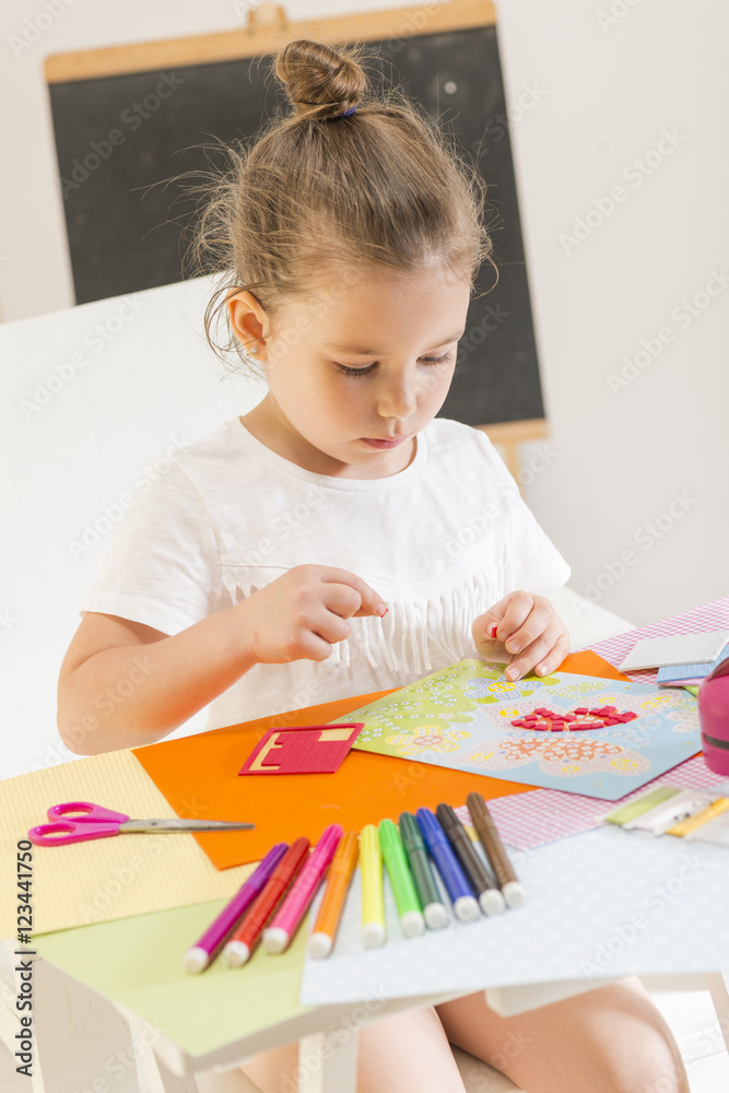 Back to school! Beautiful little girl cutting paper with scissors on ...