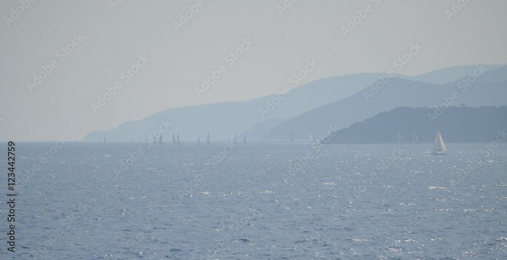 Sailing boats in the mist of blue shades of coasts of the Elba Island, Tuscany, Italy, Europe.