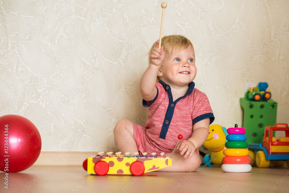 Portrait of a beautiful baby boy on the floor with car toys. 1 5 year old