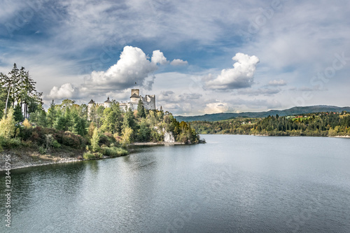 Castle on the shore of the lake in autumn day with a dramatic sky and white clouds