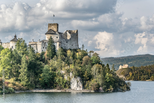Fototapeta Naklejka Na Ścianę i Meble -  Castle on the shore of the lake in autumn day with a dramatic sky and white clouds