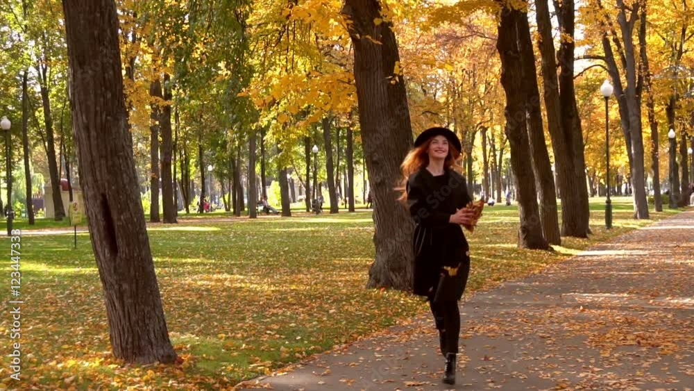 happy young girl runs in the park and throwing an autumn leaves in slow motion happy young girl runs in the park and throwing an autumn leaves in slow motion